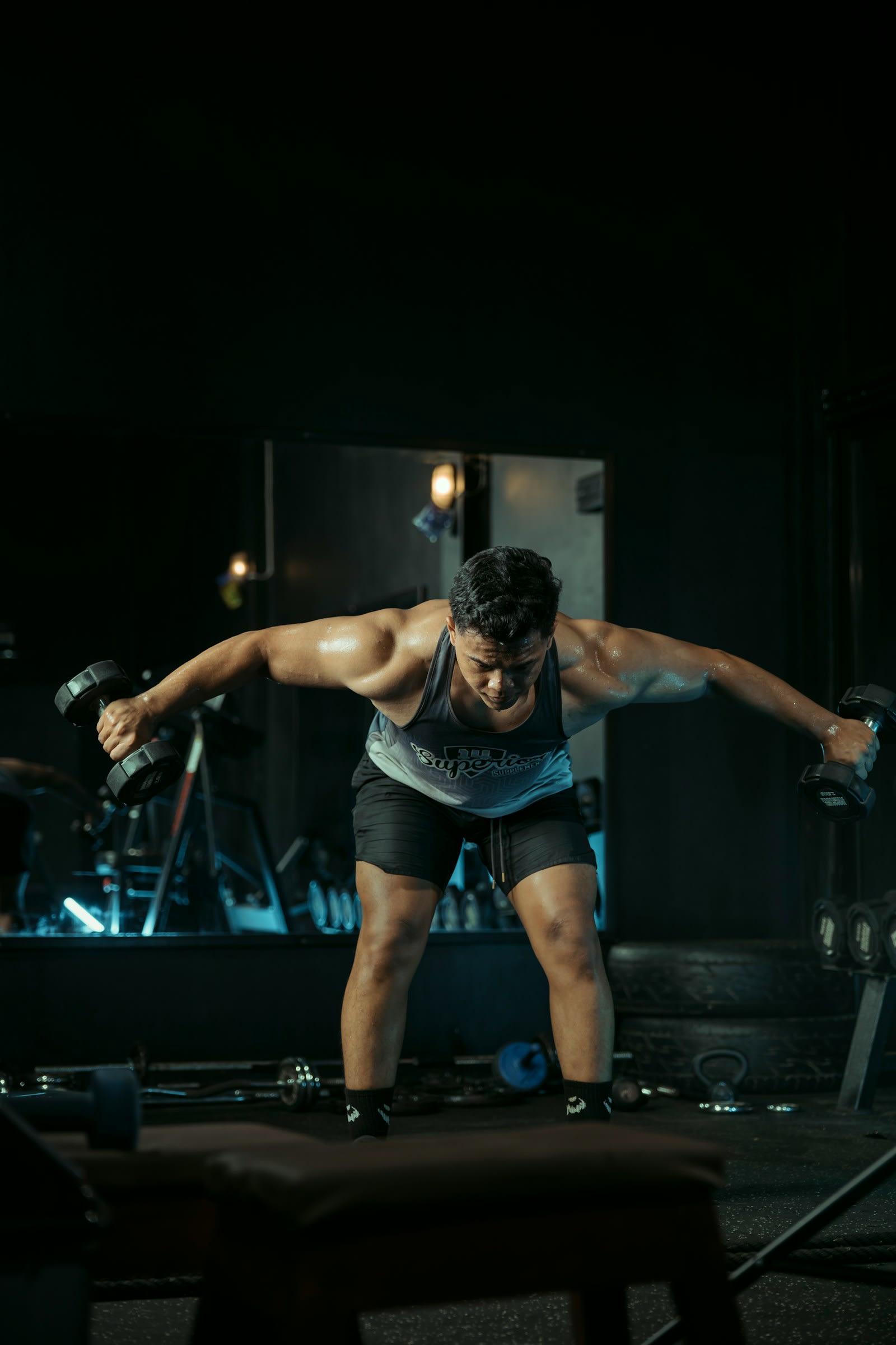 A man doing a bent-over dumbbell raise in a gym