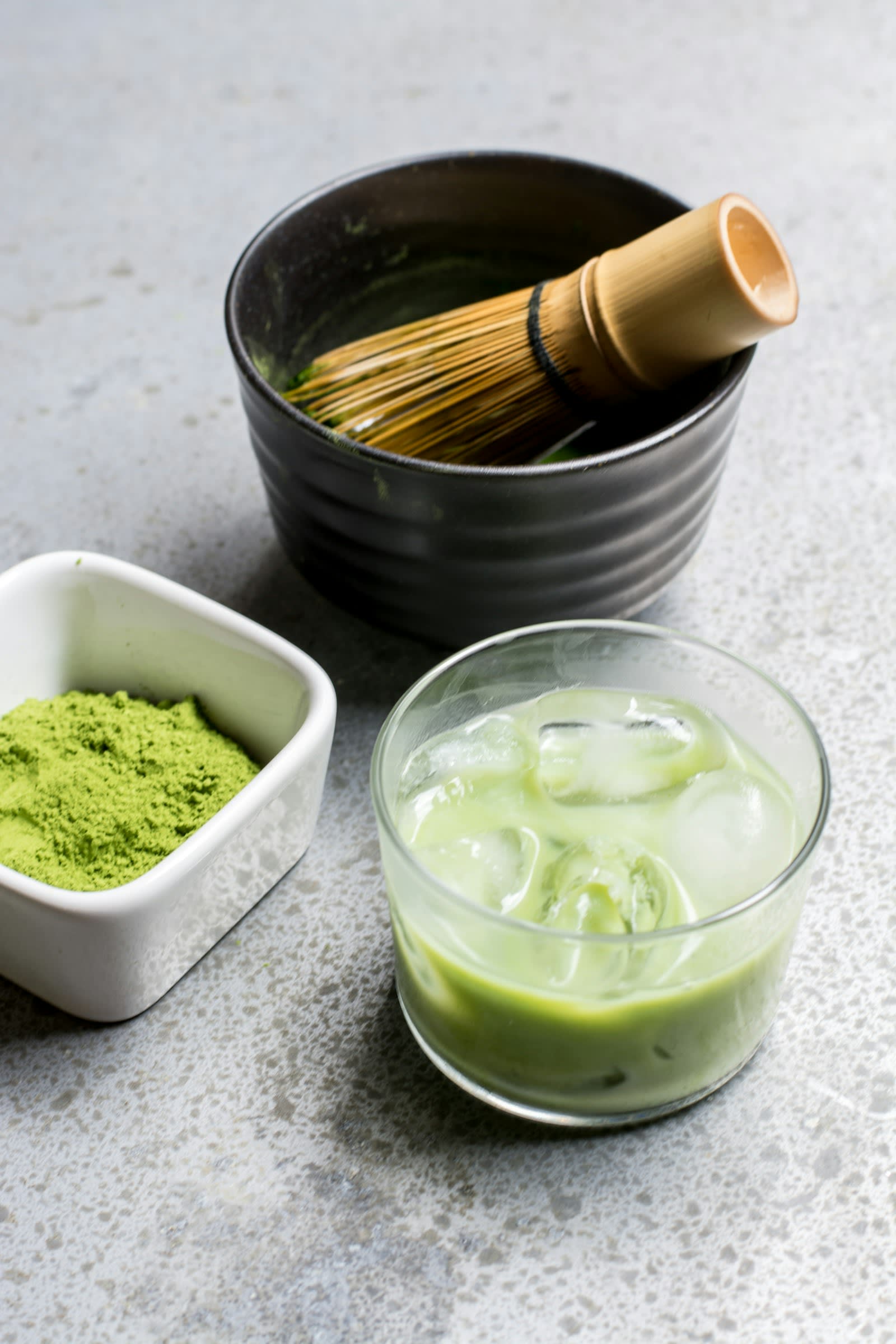 A spoonful of green powder next to a glass of green drink