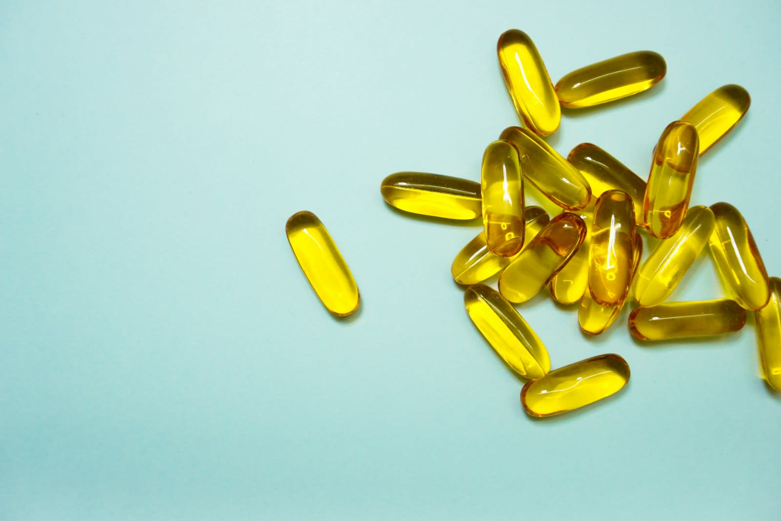Golden softgel capsules on a pale blue background